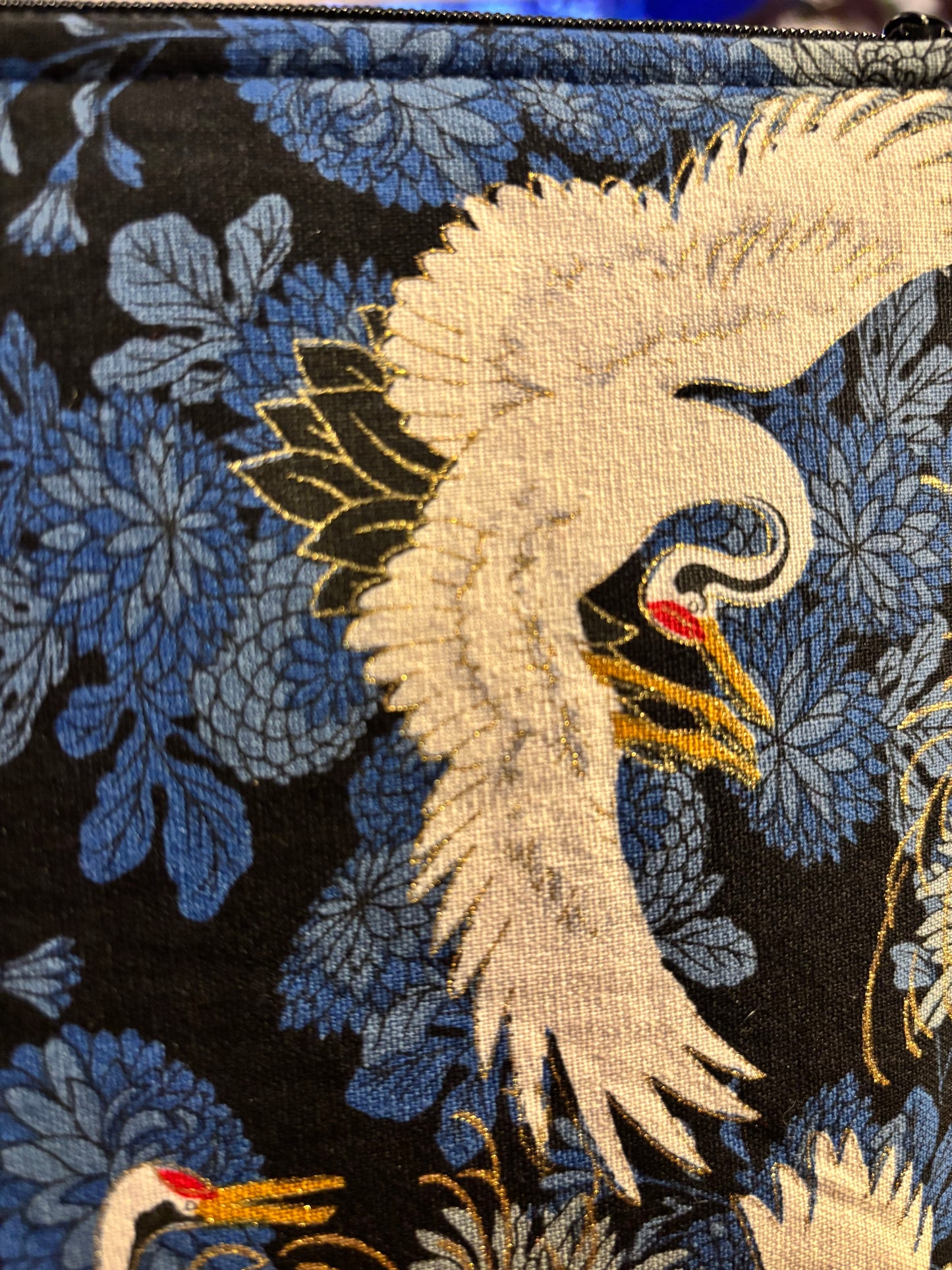 Crane print blue small makeup storage bag with gold foil detail. Gold tassel and red cotton lining.