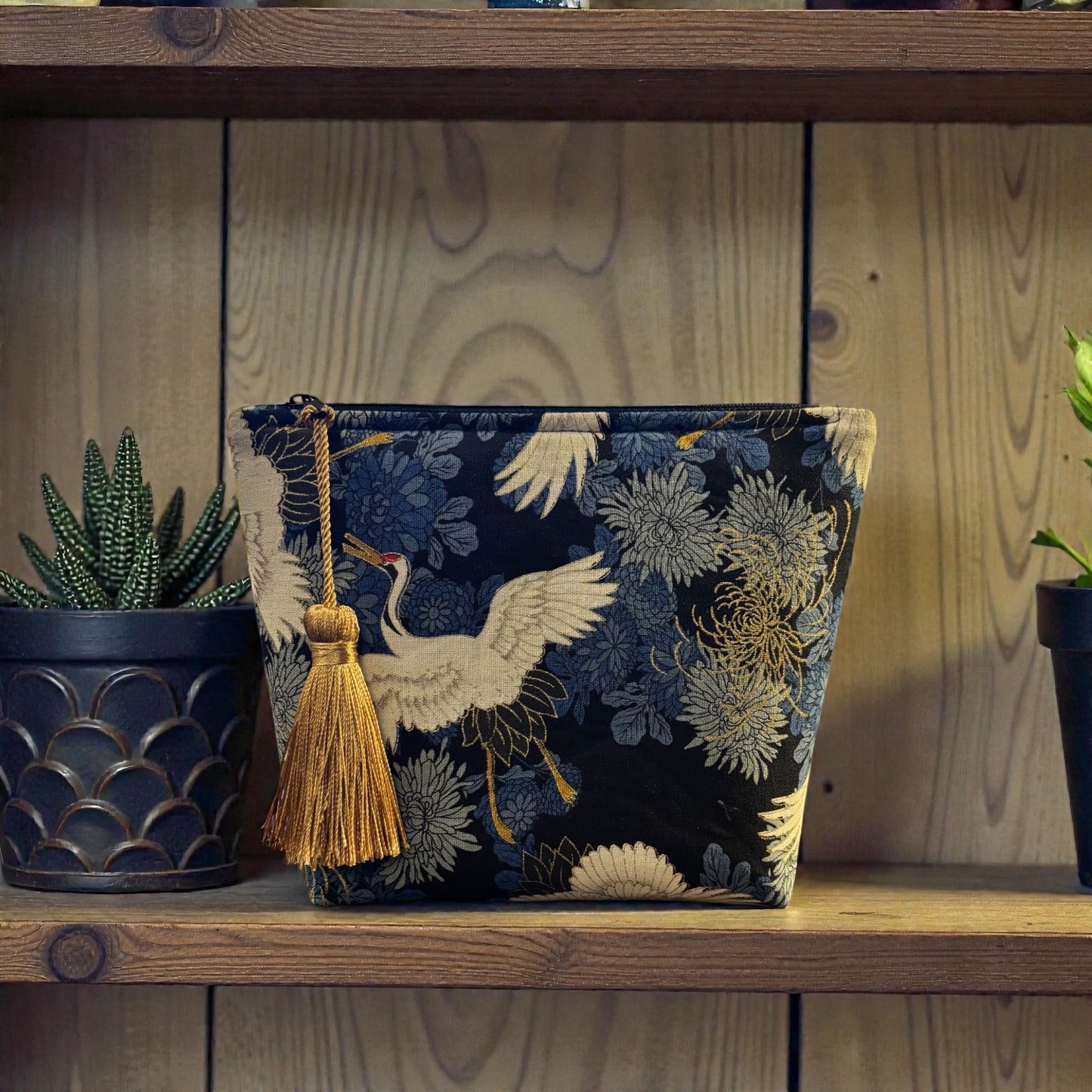 Crane print blue small makeup storage bag with gold foil detail. Gold tassel and red cotton lining.