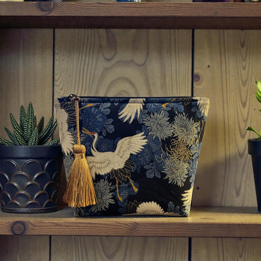 Crane print blue small makeup storage bag with gold foil detail. Gold tassel and red cotton lining.