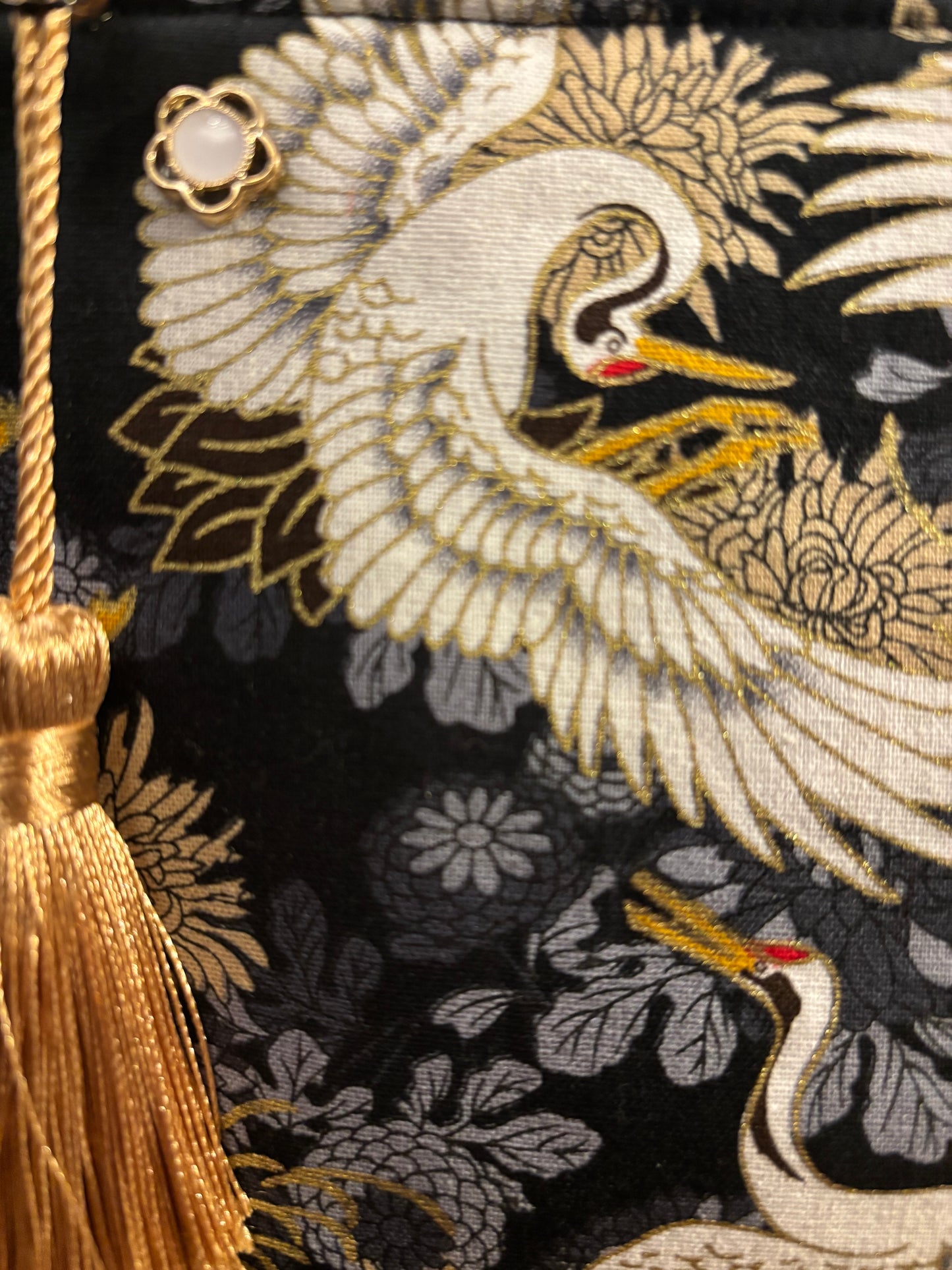 Crane print black small makeup storage bag with gold foil detail. Gold tassel and red cotton lining.